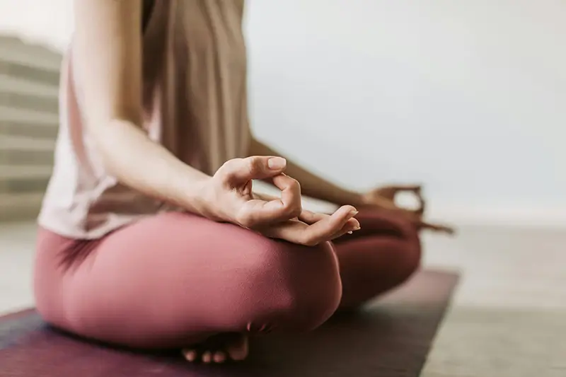 A woman sitting on the floor meditating as a way to reduce stress and anxiety.