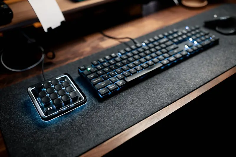 A keyboard and mouse sitting on a desk mat used to absorb hand sweat.